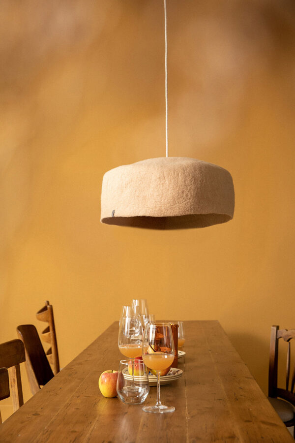 Luminaire yourte en feutre de laine couleur nude au dessus d'une table à manger